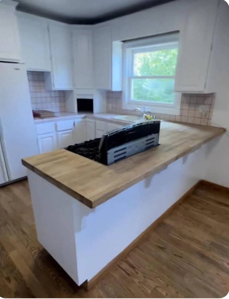 Kitchen with a stove on a counter and a window showing greenery outside.