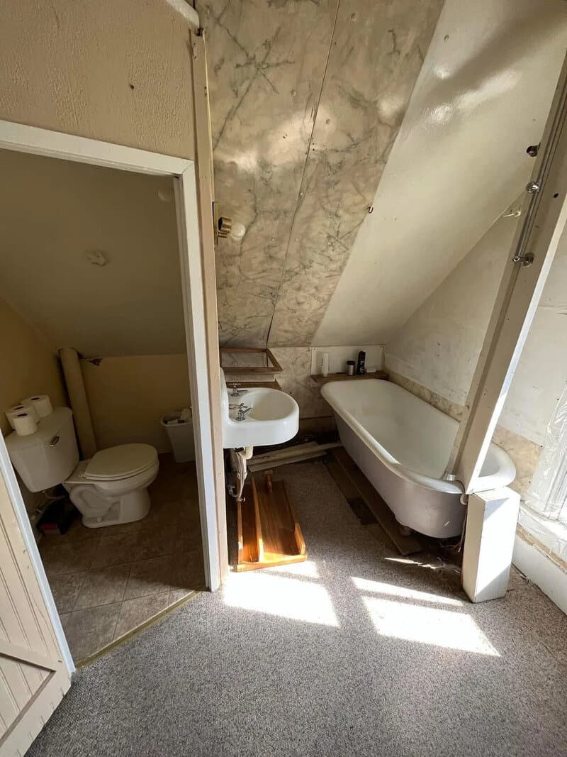 Bathroom with bathtub, sink, and toilet in a small space under a sloped ceiling.