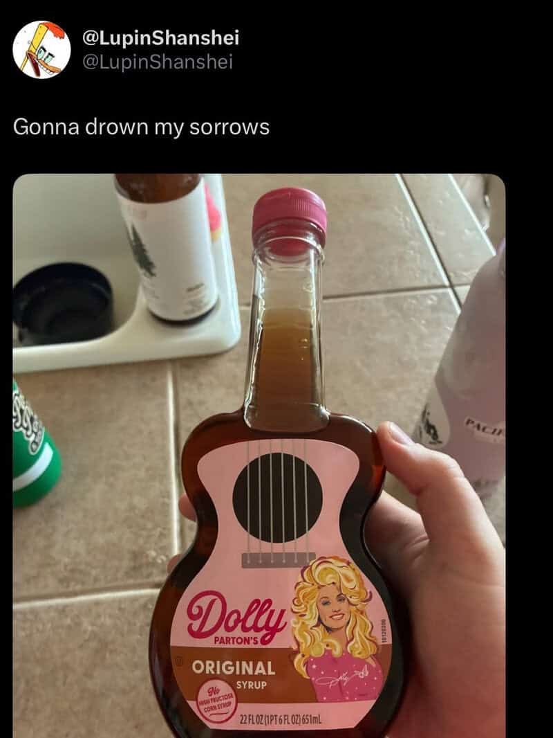Hand holding a Dolly Parton's Original Syrup bottle on a kitchen counter.