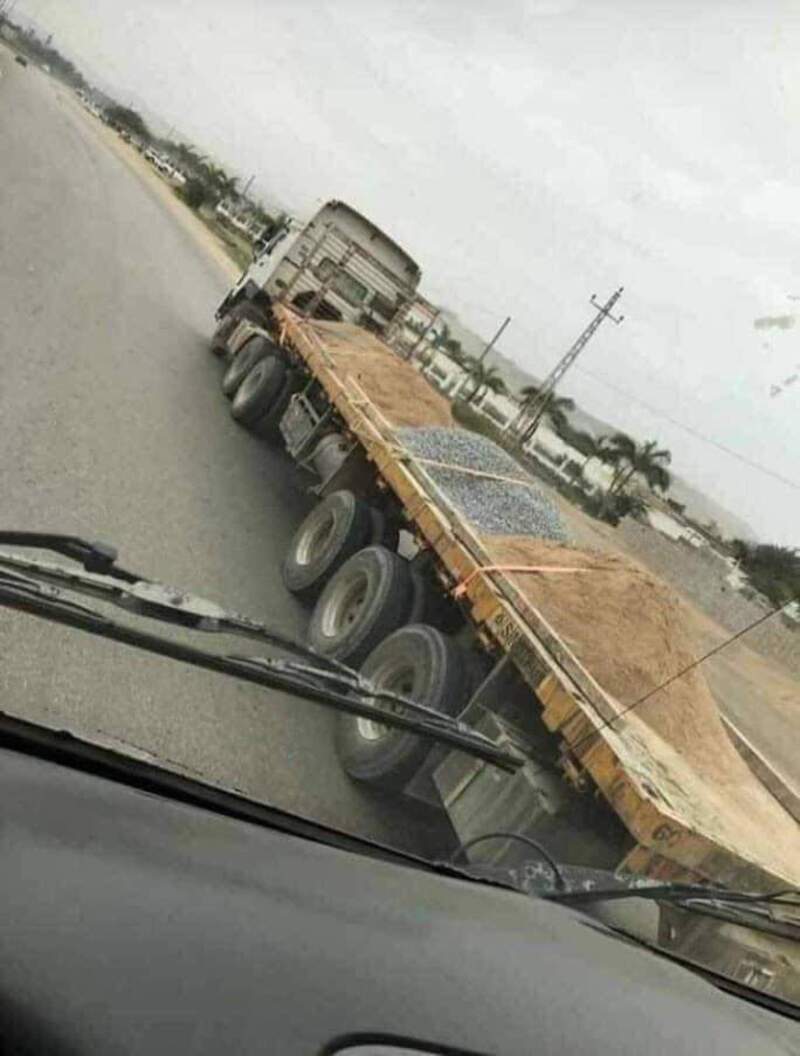 Truck tilted on its side on the road, seen from inside a vehicle.