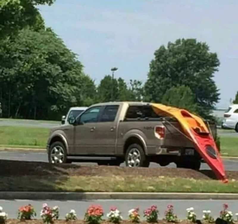 Car with a kayak attached, blocking the parking space.