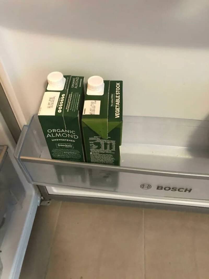 Two cartons of organic almond milk placed on a refrigerator shelf.