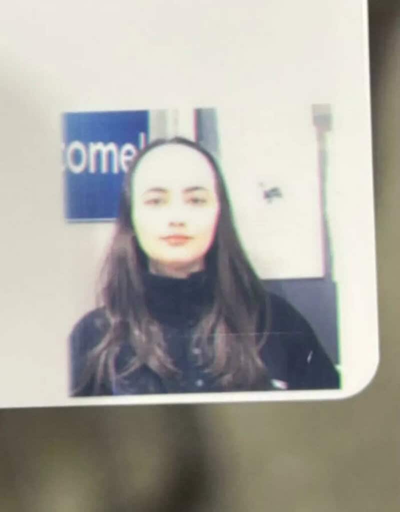 Blurry photo of a woman with long dark hair in front of a sign.