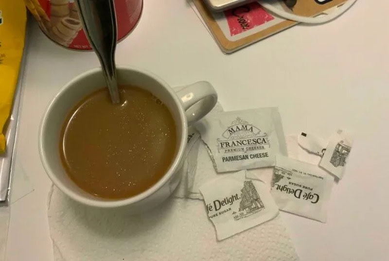 Coffee mug with tea bag tags and a spoon on a table.