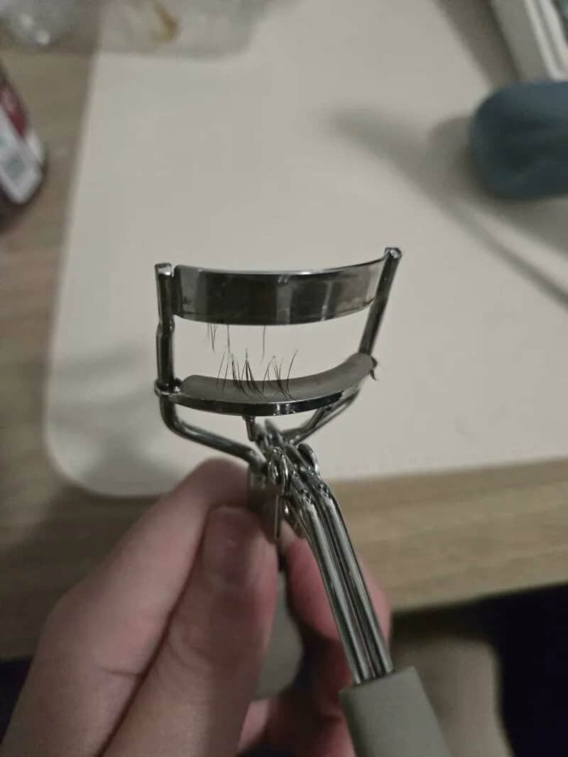 Broken eyelash curler with bent metal and damaged rubber pad.