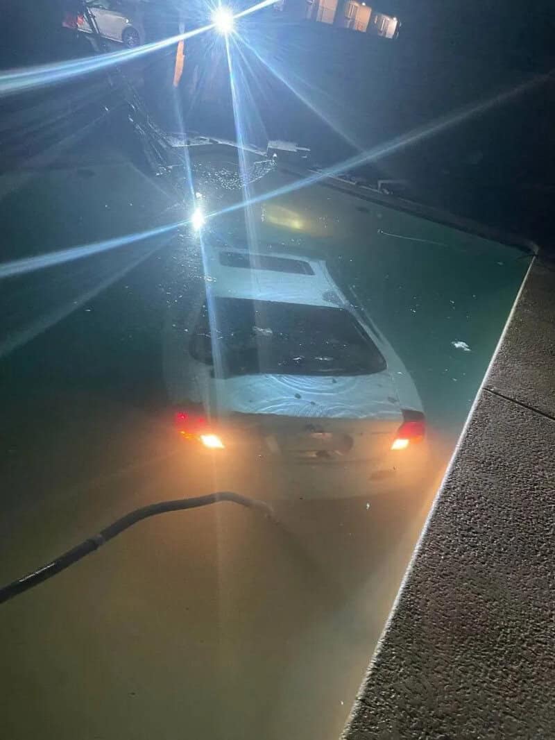 Car parked on the street with a bright light reflection and a cracked windshield.