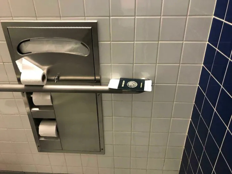A smartphone is placed on a toilet paper dispenser in a bathroom.