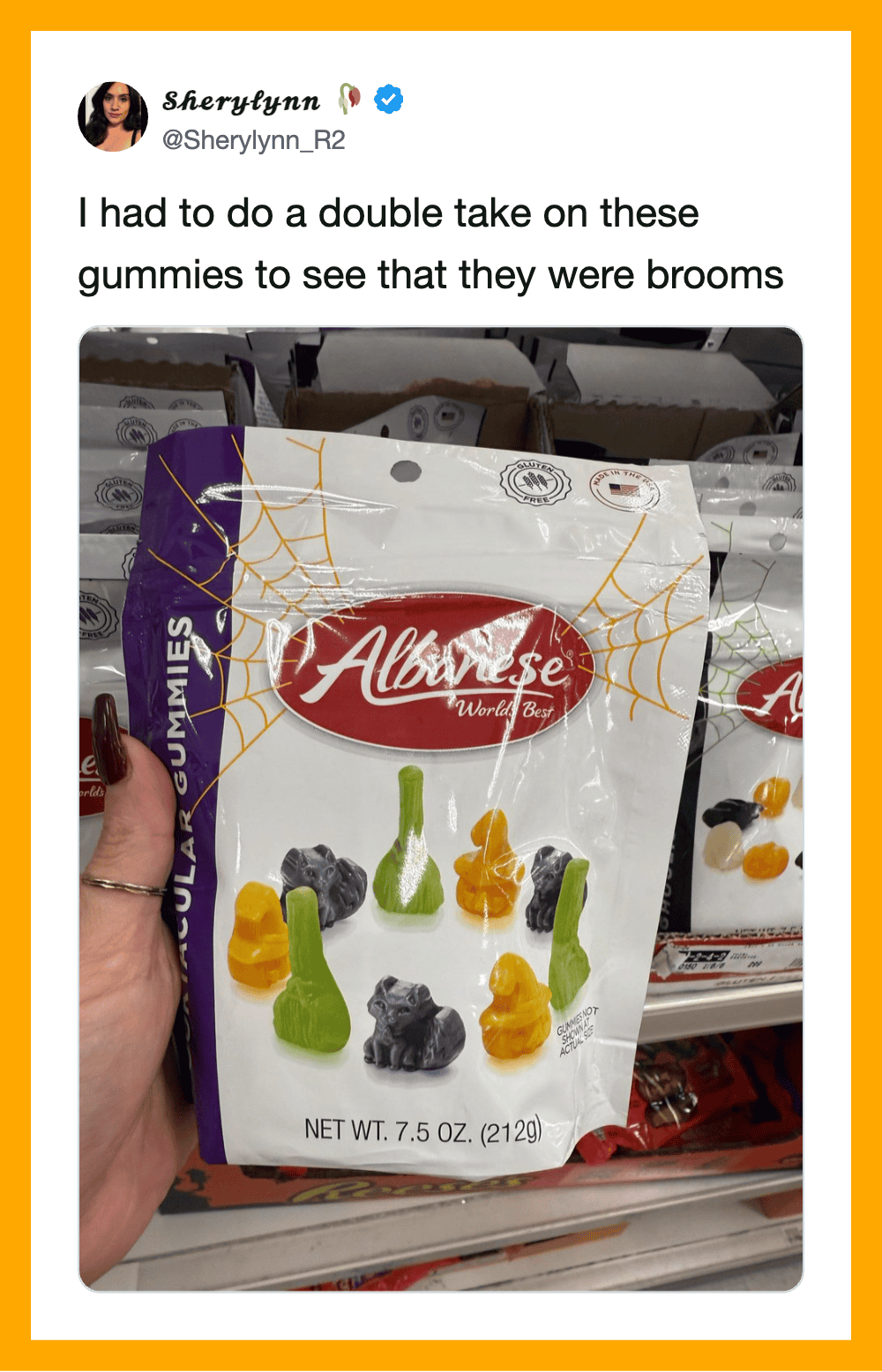 Person holding a bag of gummy candies shaped like brooms, with a store shelf in the background.