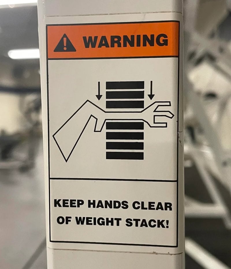 Warning sign showing weight stack with arrows and a hand, keep hands clear.