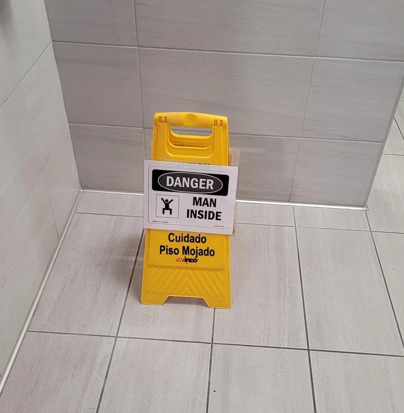 Warning sign in English and Spanish: 'Danger Man Inside' and 'Cuidado Piso Mojado'.