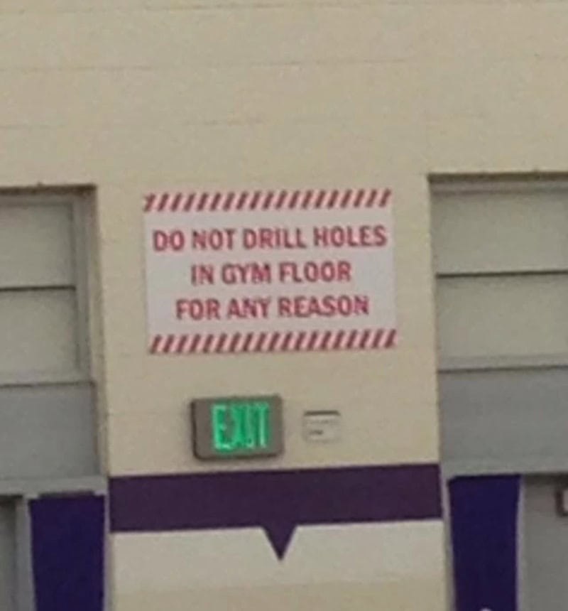 Do not drill holes in gym floor for any reason sign with green exit sign below.