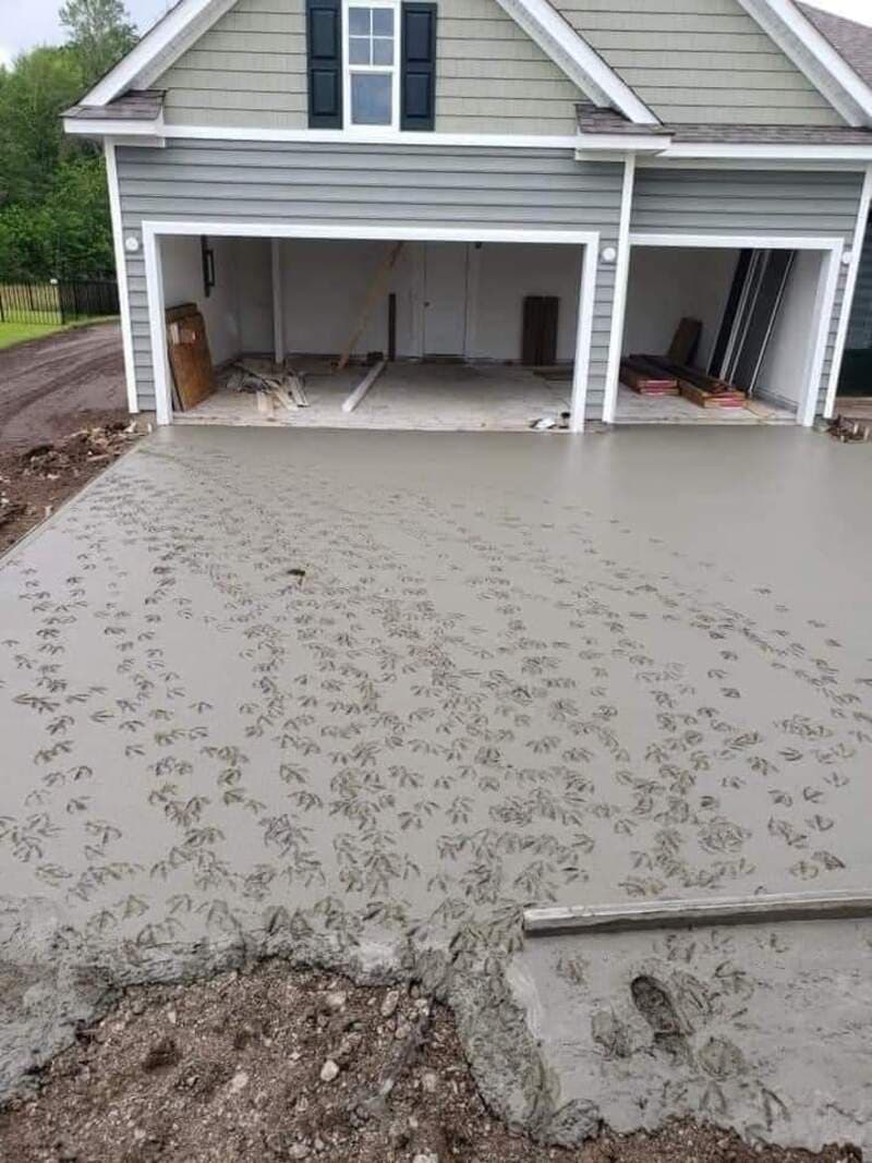 Concrete driveway with footprints in front of a garage under construction.