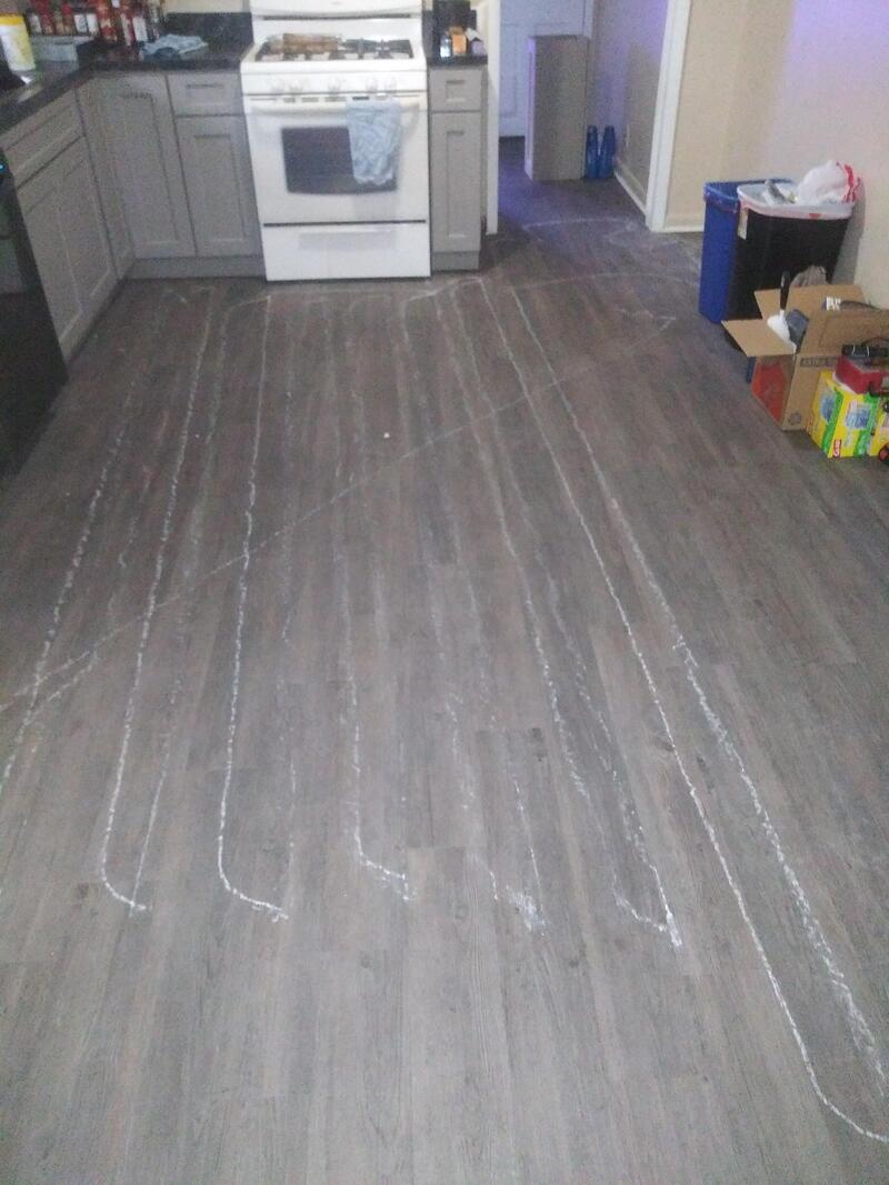 Kitchen floor with white chalk lines drawn on it, near boxes and appliances.