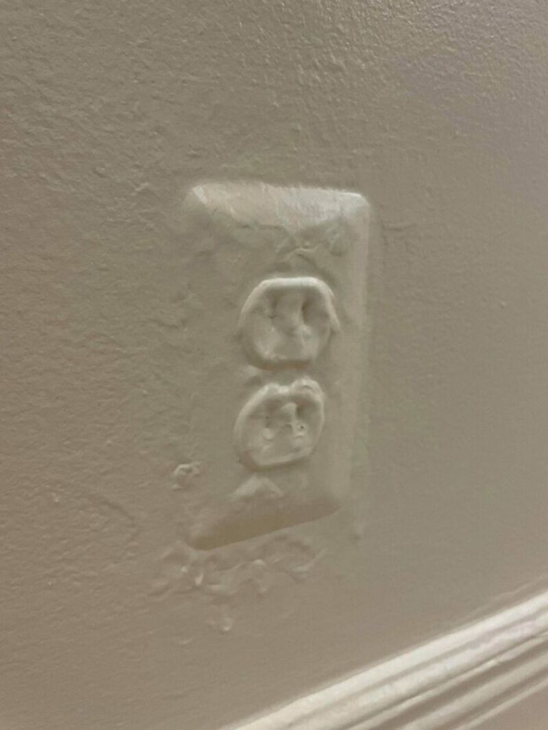 Broken wall outlet with damaged cover plate in a wall.