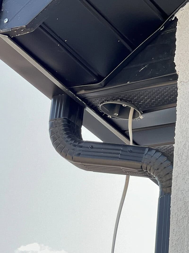 Drain pipe and cable under a building's eaves with a humorous angle.