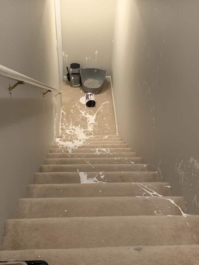 Spilled paint on stairs and floor at the bottom of a narrow staircase.