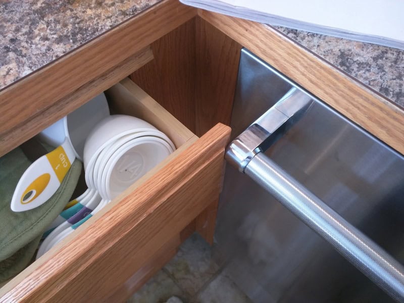 Kitchen drawer with utensils and a hidden trash bag inside.