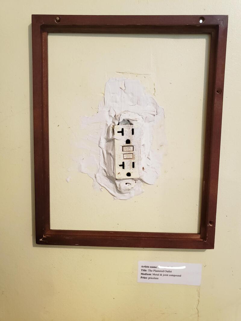 Broken electrical outlet in a wall with a wooden frame around it.