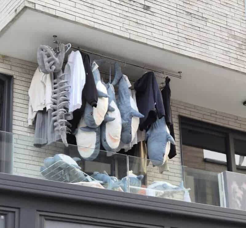 Clothes and shoes hanging on a balcony railing, with some socks and slippers.