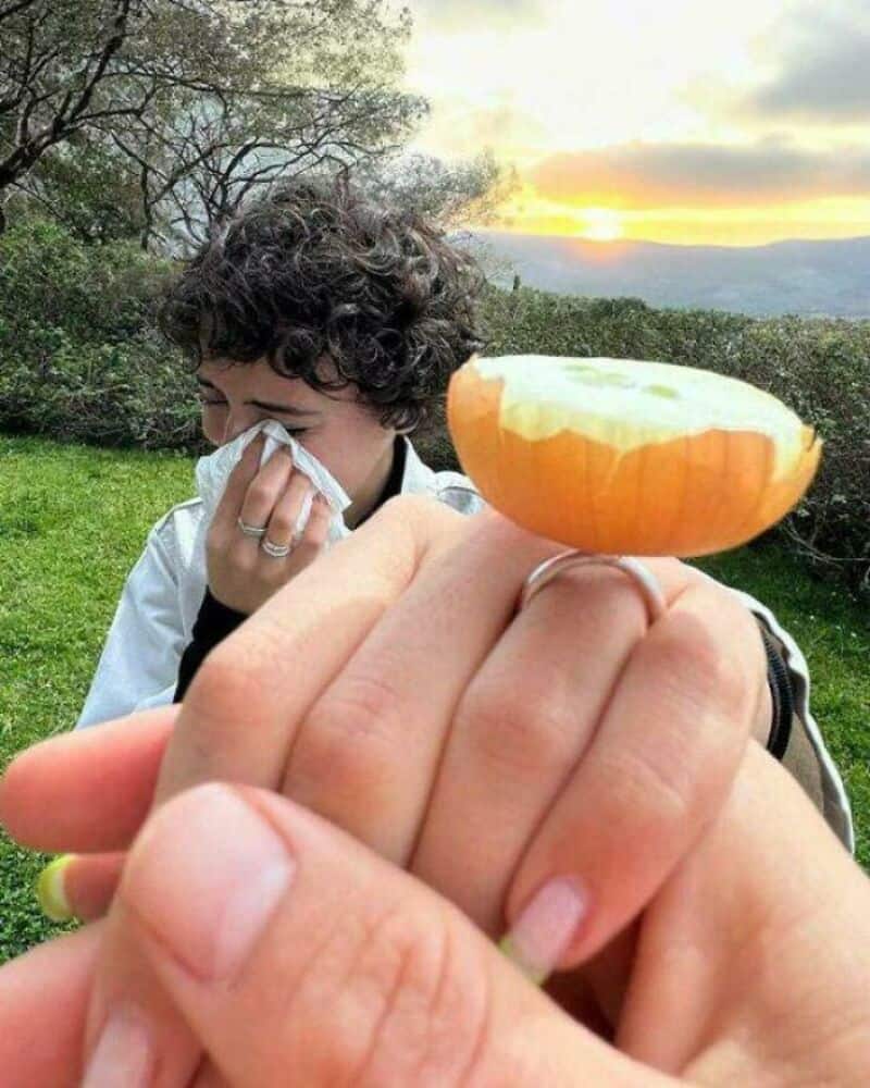 Person holding a half orange with a sunset background.