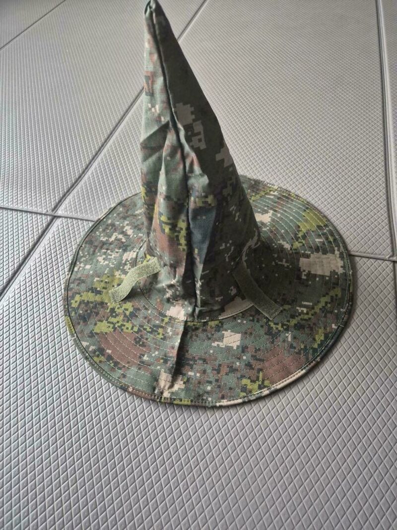 Camouflage hat with a tall, pointed top on a tiled floor.