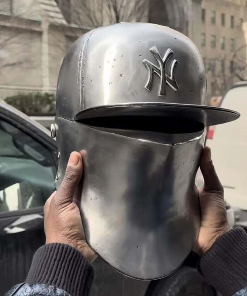 Metal helmet with a New York Yankees cap and a slit for the eyes.