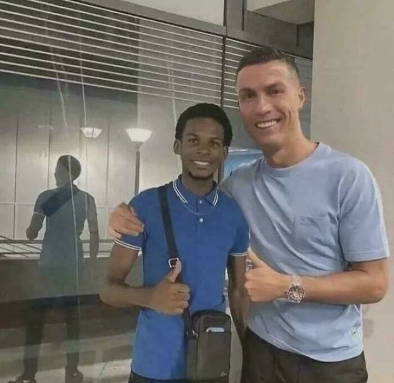 Two men smiling, one giving a thumbs up, in an indoor setting.