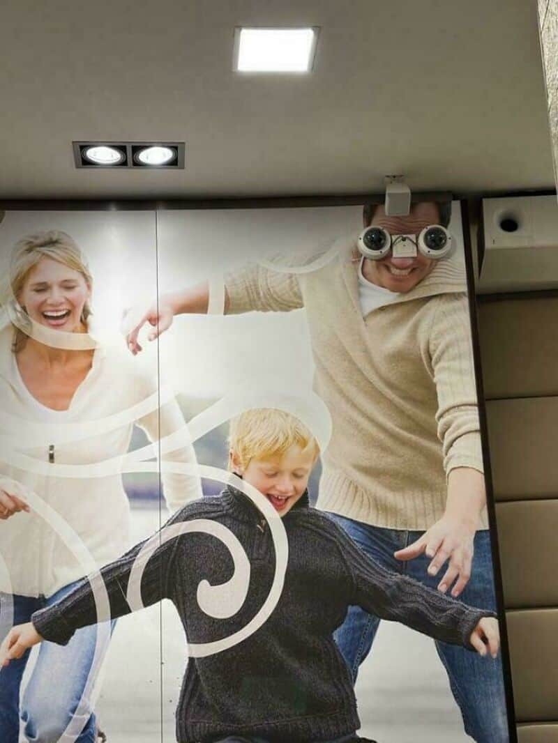 People taking a fun photo with a mirror and a camera with funny glasses.
