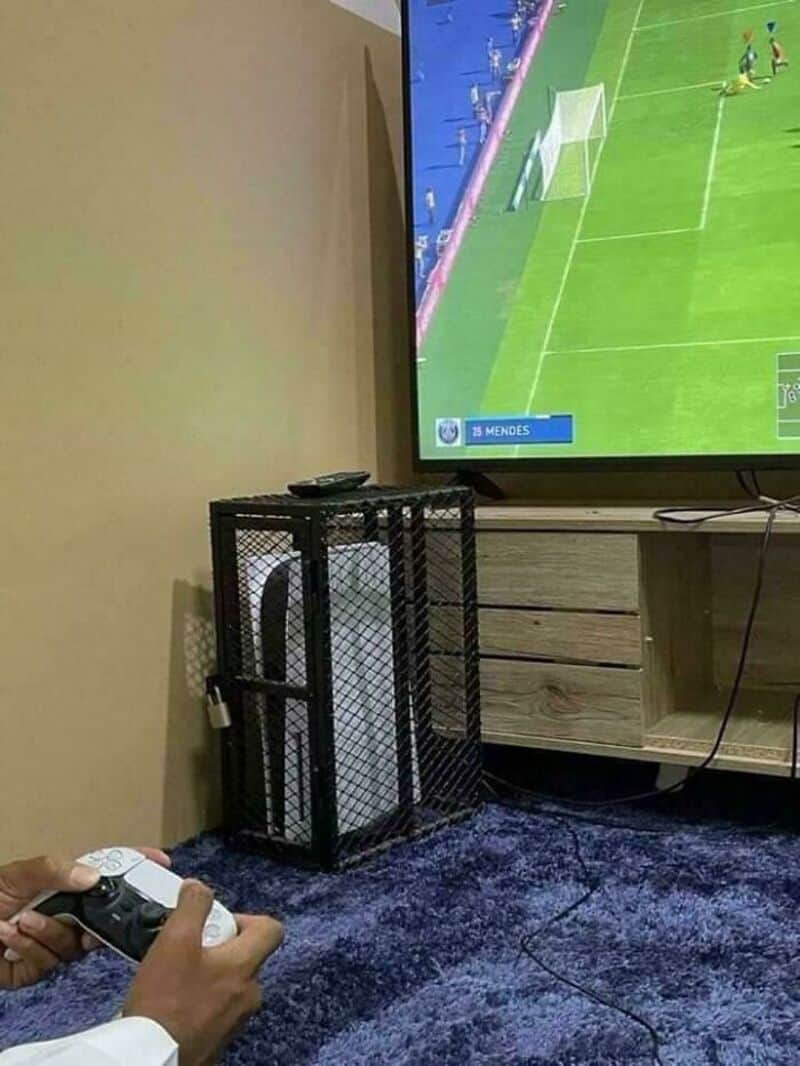 Person playing video game on TV with a black cage around the console.