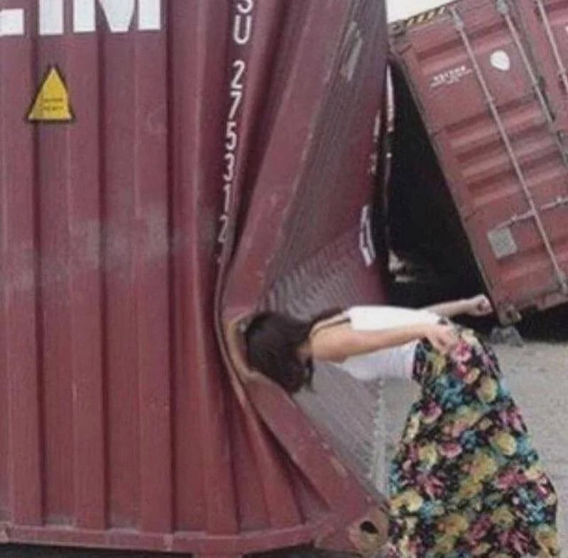 Woman with long hair leaning into a tilted shipping container.