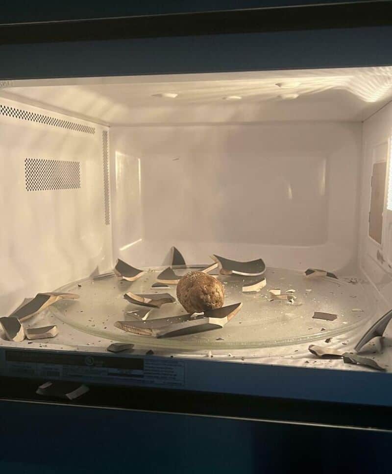 Empty microwave with broken glass and a meatball inside.