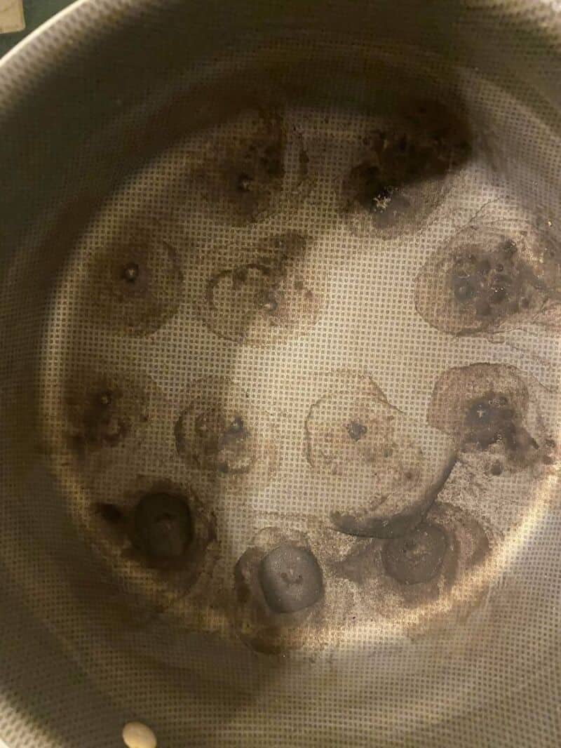 Burnt food in a pot with a smiley face pattern of burnt spots.