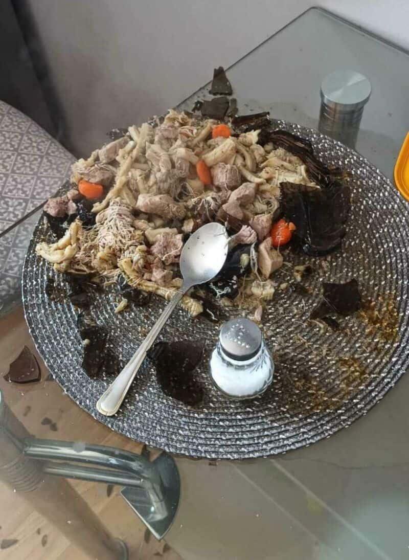 Burnt food on a plate with a spoon, salt shaker, and blackened pieces.