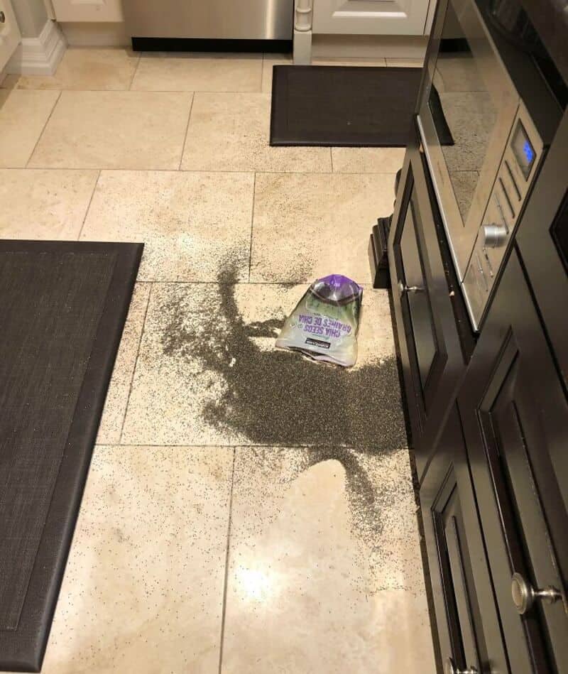 Spilled purple powder on kitchen floor with a bag of baking soda nearby.