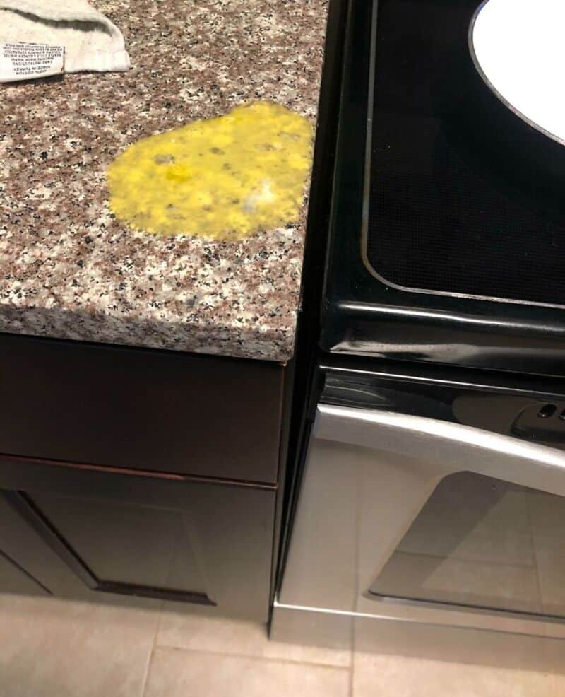 Spilled egg on kitchen counter next to stove in a kitchen.