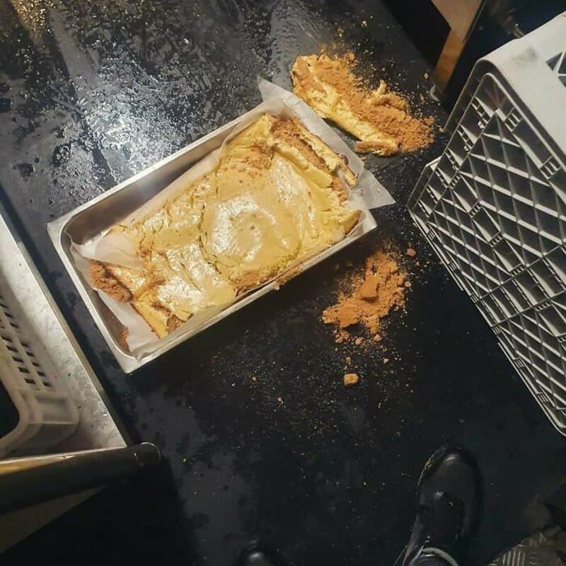 Messy kitchen with spilled crumbs and a damaged baking tray with a broken cake.