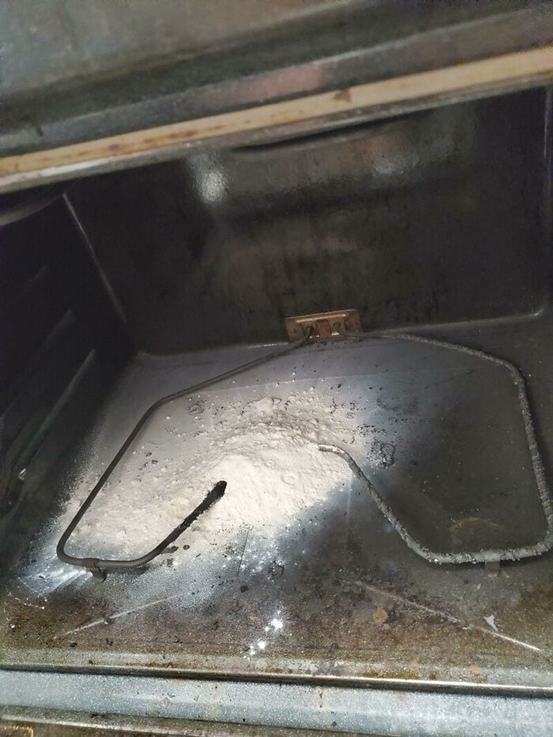 Inside a burnt oven with a broken oven rack and burnt debris.