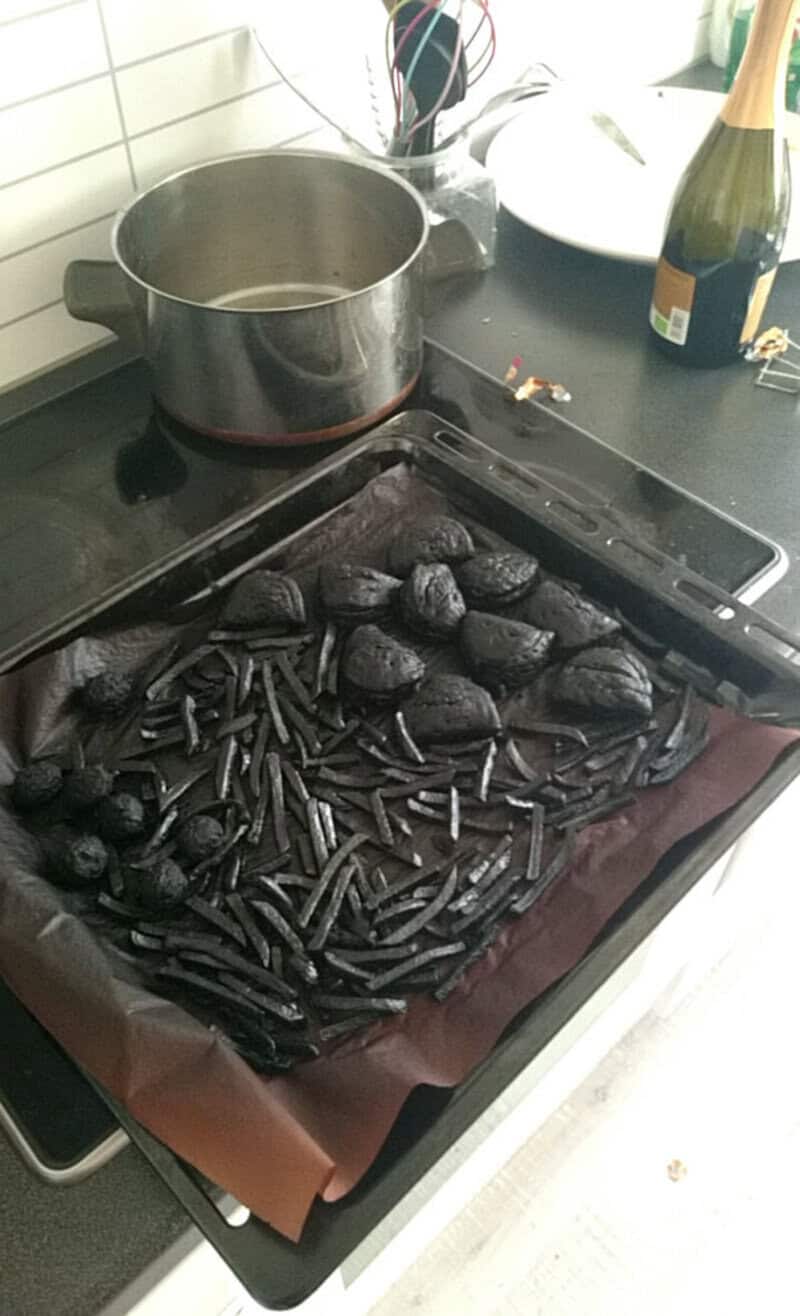 Burnt black food on stovetop with pot and champagne bottle nearby.