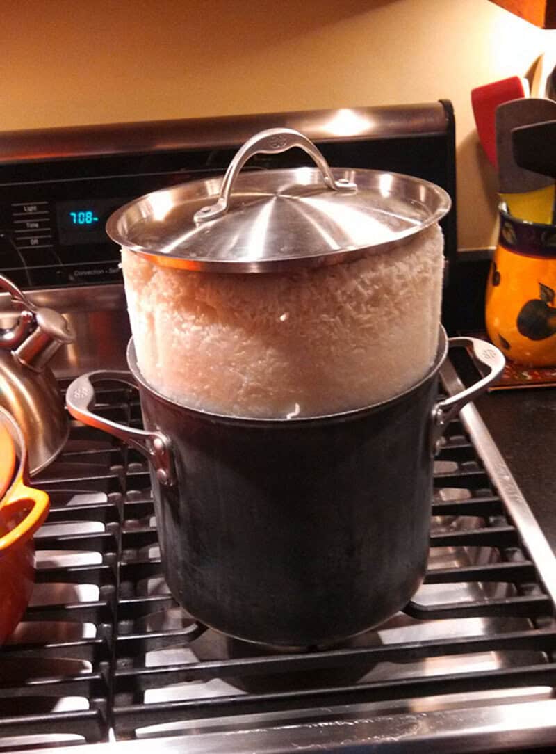 Pot on stove with rice overflowing and spilling over the sides.