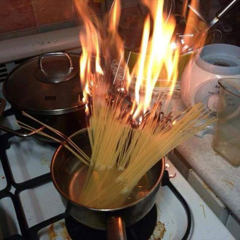 Spaghetti catches fire in a pan on the stove.
