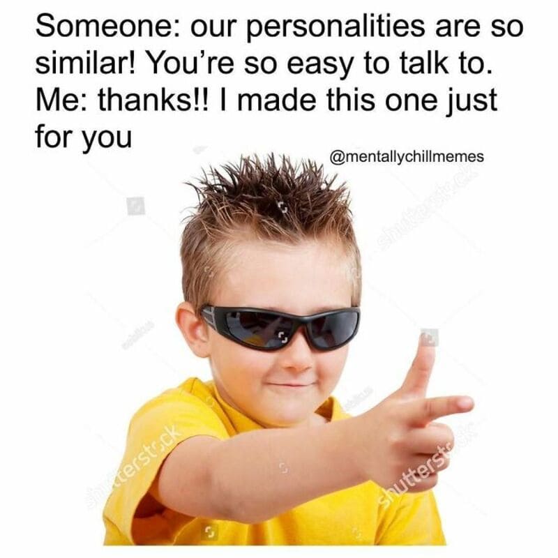 Child in yellow shirt wearing sunglasses, making a finger gun gesture.