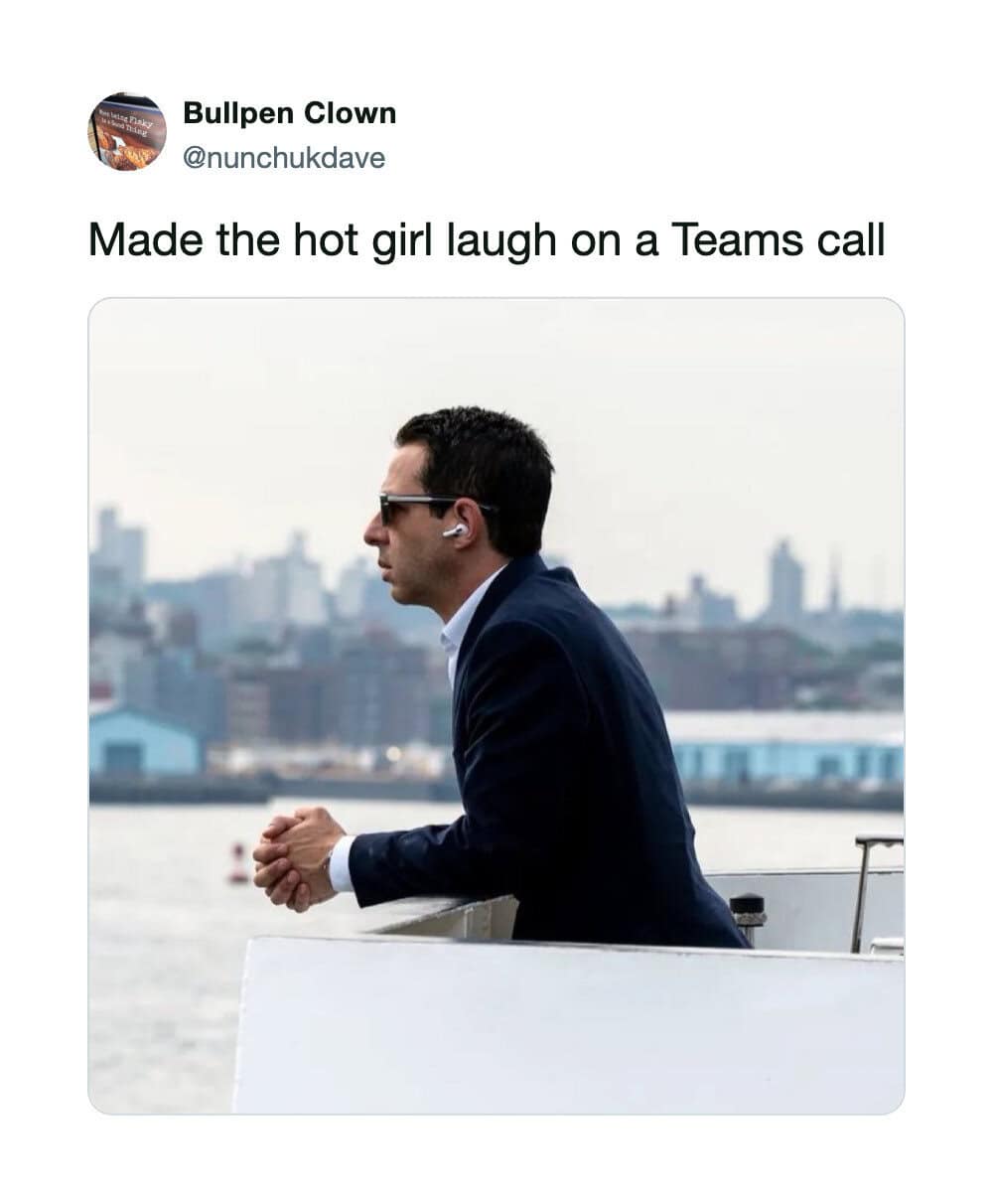 Man in suit laughing on a Teams call with city skyline in background.