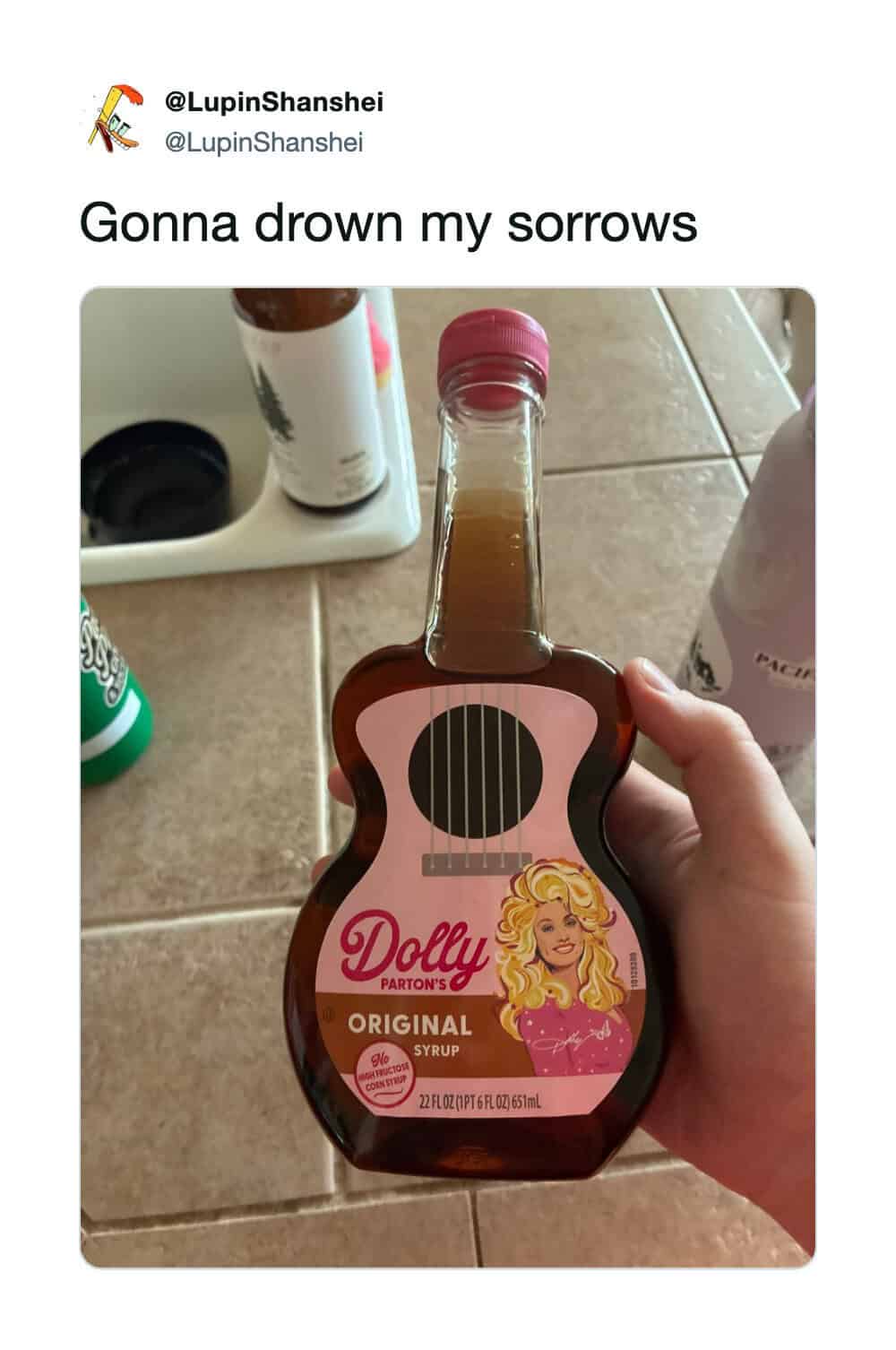 Hand holding a Dolly Parton syrup bottle shaped like a guitar.
