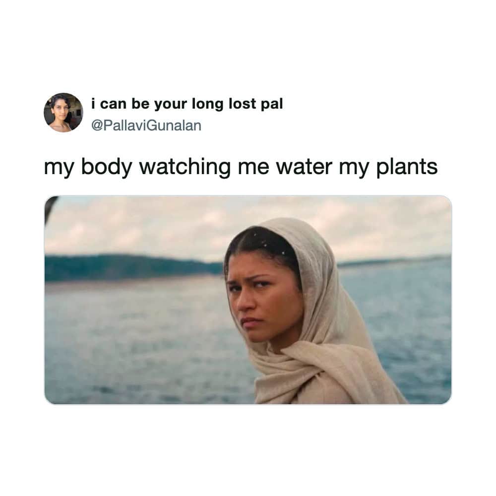 A woman with a headscarf looking at water with a serious expression.