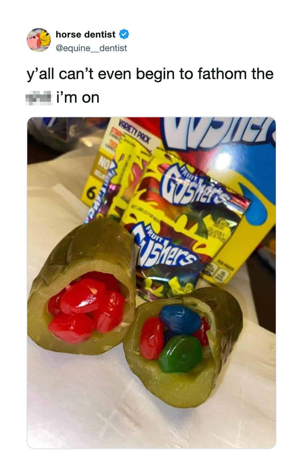 A photo of two green gummy candies filled with red, blue, and green candies, with candy packages in.