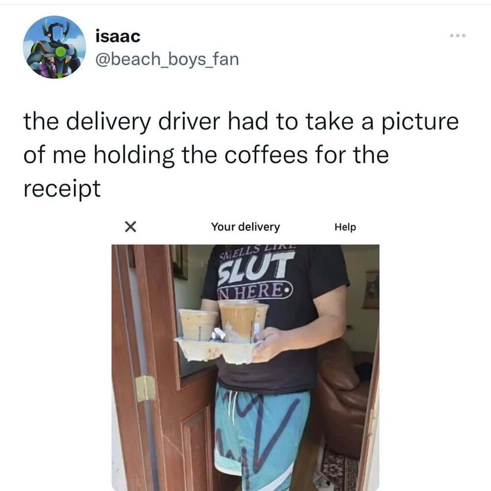 Delivery person holding coffees for the receipt, wearing a black shirt with text.