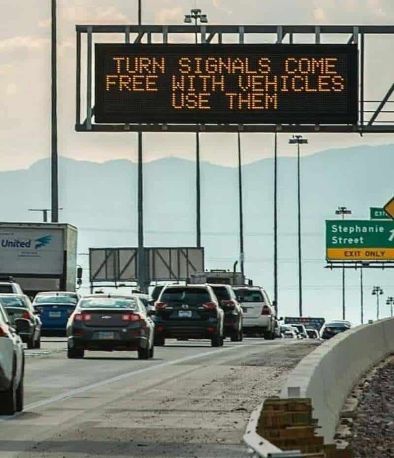 Electronic sign on highway says 'TURN SIGNALS COME FREE WITH VEHICLES USE THEM'.