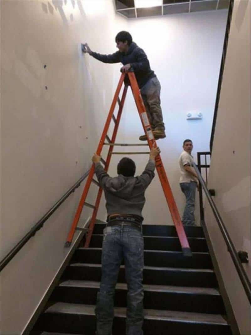 Three boys on a staircase, one on a ladder, one holding it, and one leaning on the wall.