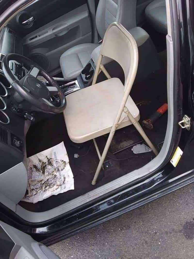Chair placed on car floor with a paper and dirt underneath.