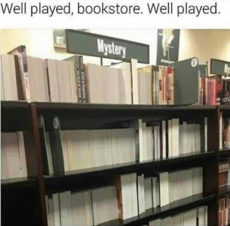 Bookshelf labeled 'Mystery' with mostly empty shelves in a bookstore.